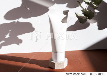 White cosmetic cream tube on wooden geometric pedestal podium, product packaging with natural shadows from plants, body scrub, moisturizing clear, shampoo mockup, biophilic concept. 81854096