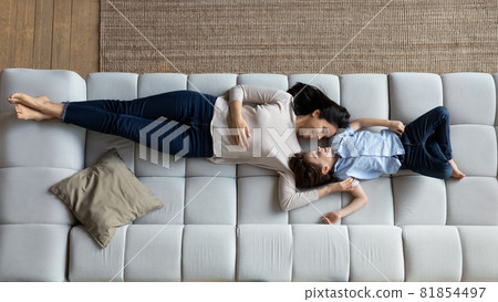 Peaceful young korean asian mother resting on sofa with child. Peaceful young korean asian mother resting on sofa with child. 81854497