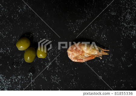 frozen shrimp and olives close-up on a dark background 81855336