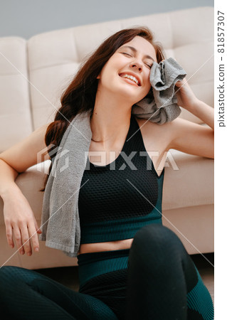 Young athlete wipes her sweat with a towel after fitness at home. Young athlete wipes her sweat with a towel after fitness at home. 81857307