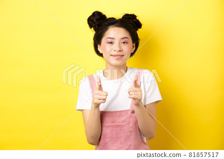 Cheerful teen asian girl pointing fingers at camera and smiling, encourage or invite you, making compliment, praise nice work, standing on yellow background Cheerful teen asian girl pointing fingers at camera and smiling, encourage or invite you, making compliment, praise nice work, standing on yellow background 81857517