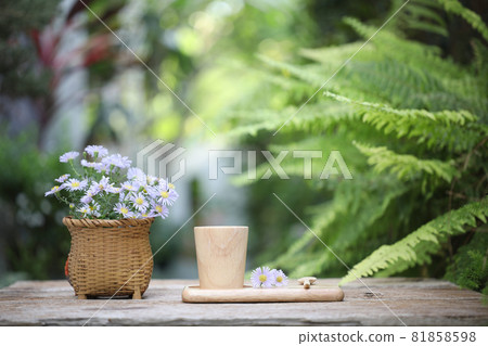 Wooden cup on wooden plate with purple aster flowers on wooden table and fern leaves Wooden cup on wooden plate with purple aster flowers on wooden table and fern leaves 81858598