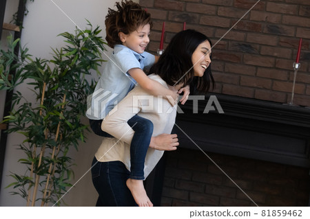 Happy young korean mother holding on back cute son. 81859462