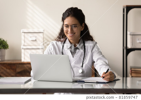 Happy young female GP doctor using laptop, making video call 81859747