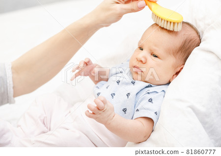 Mother brushing hair of newborn baby with soft brush 81860777