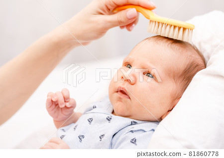 Mother brushing hair of newborn baby Mother brushing hair of newborn baby 81860778