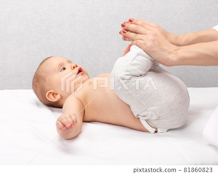 Little baby receiving osteopathic treatment of her leg to prevent hip dysplasia by pediatric physiotherapist 81860823