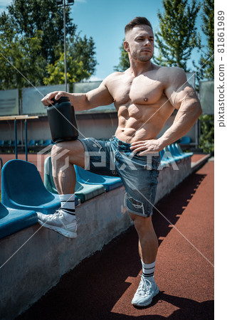 attractive muscular athlete with protein whey powder in black container outdoor 81861989