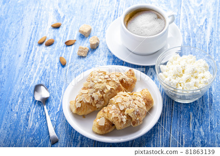 Breakfast, fresh French croissant with a cup of coffee and cottage cheese on a blue wooden table. 81863139