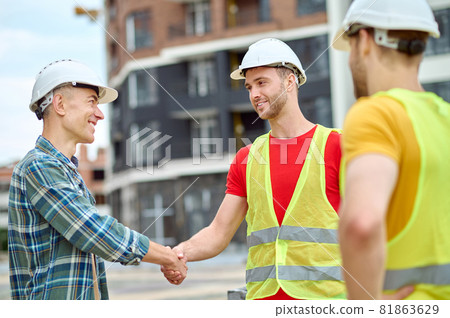 Handsome bearded Caucasian construction worker shaking his colleague hand Handsome bearded Caucasian construction worker shaking his colleague hand 81863629