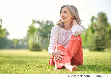 Adult pretty woman meditating on lawn in park 81863997