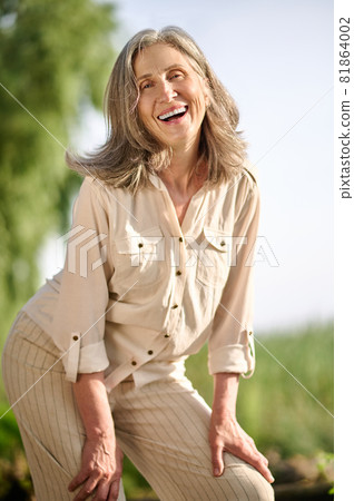 Cheerful woman of retirement age on walk Cheerful woman of retirement age on walk 81864002