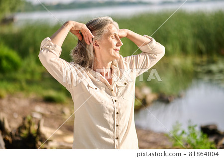 Woman with closed eyes near pond in nature Woman with closed eyes near pond in nature 81864004