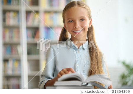 Happy cute schoolchild standing at a desk with books 81864369