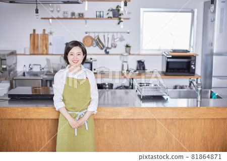 穿著圍裙站在廚房裡的年輕女人 81864871