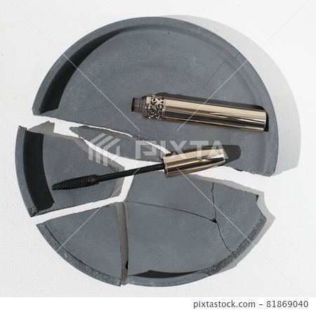 lash mascara on a broken cement tray. open golden mascara tube on concrete background. female beauty and cosmetic tools. lash mascara on a broken cement tray. open golden mascara tube on concrete background. female beauty and cosmetic tools. 81869040