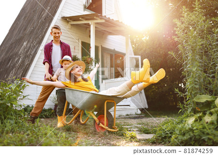 Excited family playing with wheelbarrow 81874259