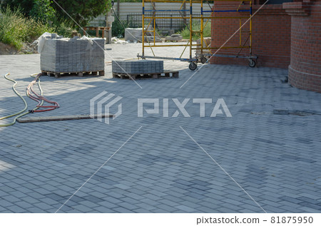 Pallets of cement blocks. Yellow scaffolding. Red brick building. Water hoses. Construction Industry. Architecture. Pallets of cement blocks. Yellow scaffolding. Red brick building. Water hoses. Construction Industry. Architecture. 81875950