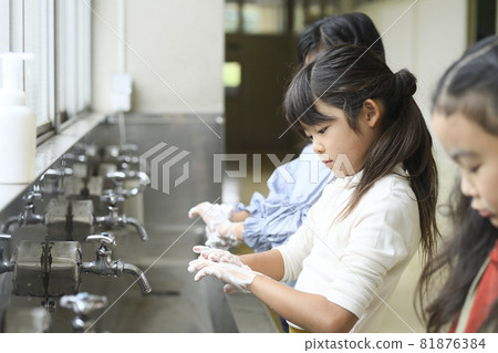 Elementary school girl washing hands at school Elementary school girl washing hands at school 81876384