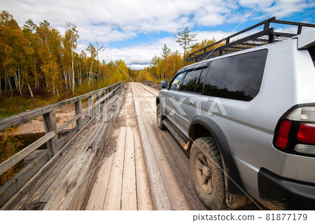 Mitsubishi Pajero Sport on wooden bridge in autumn forest 81877179