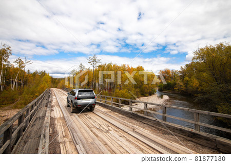 Mitsubishi Pajero Sport on wooden bridge in autumn forest 81877180