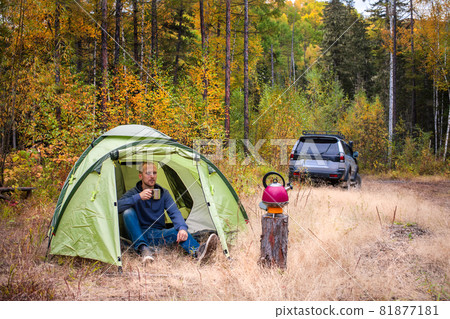 Sukpai, Russia - September 16, 2017: Man drinking tea at tourist tent in autumn forest 81877181