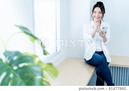 A young woman using a smartphone in the living room 81877892