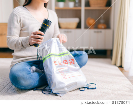 A woman who puts a flashlight in an emergency bag 81878074