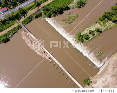 Negai Bridge, a submersible bridge adjacent to a row of cherry blossom trees near the embankment of the Hiikawa River in Kisuki-cho, Unnan City, Shimane Prefecture, after a heavy rain from a bird's perspective Negai Bridge, a submersible bridge adjacent to a row of cherry blossom trees near the embankment of the Hiikawa River in Kisuki-cho, Unnan City, Shimane Prefecture, after a heavy rain from a bird's perspective 81878353
