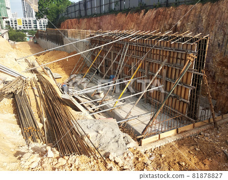 PENANG, MALAYSIA -MARCH 5, 2021: Reinforce Concrete retaining wall construction is in progress. Workers fabricated the timber formwork before pouring the concrete inside it.  81878827