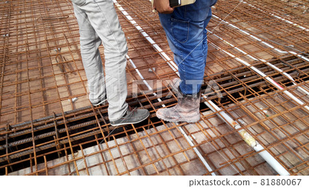 PENANG, MALAYSIA -AUGUST 23, 2020: Construction workers wearing steel toe safety shoes standing on top of the steel reinforcement bar. These shoes protect against foot injuries on construction sites. PENANG, MALAYSIA -AUGUST 23, 2020: Construction workers wearing steel toe safety shoes standing on top of the steel reinforcement bar. These shoes protect against foot injuries on construction sites. 81880067