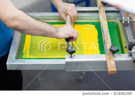 Serigraphy silk screen print process at clothes factory. Frame, squeegee and plastisol color paints 81880206