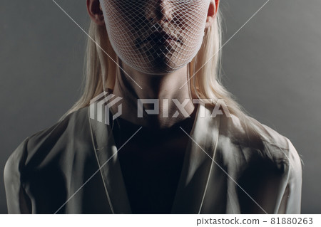Closeup portrait of white caucasian albino blond woman fashion model wearing quarantine medical face mask coarse mesh net on grey background. Covid-19 coronavirus protection concept Closeup portrait of white caucasian albino blond woman fashion model wearing quarantine medical face mask coarse mesh net on grey background. Covid-19 coronavirus protection concept 81880263