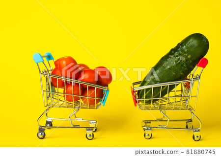 tomatoes and cucumbers in shopping baskets. on a yellow background. copy space tomatoes and cucumbers in shopping baskets. on a yellow background. copy space 81880745