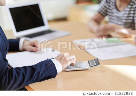 At hand of the insurance salesman who calculates with a calculator At hand of the insurance salesman who calculates with a calculator 81882988