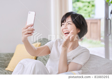 A young lady watching a smartphone on a sofa A young lady watching a smartphone on a sofa 81883201
