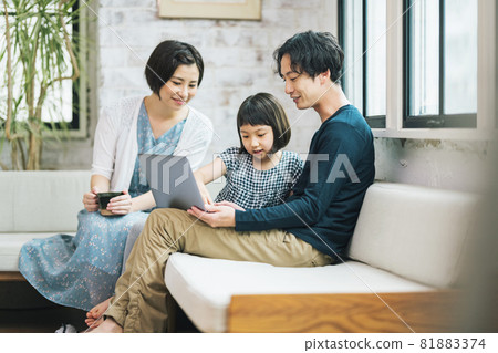 Family looking at a laptop on the sofa at home 81883374