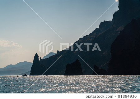 The Republic of Crimea. July 21, 2021. Picturesque view of the silhouettes of Ivan the Robber rocks and the Golden Gate at the foot of Kara-Dag Mountain near the city of Koktebel. The Republic of Crimea. July 21, 2021. Picturesque view of the silhouettes of Ivan the Robber rocks and the Golden Gate at the foot of Kara-Dag Mountain near the city of Koktebel. 81884930