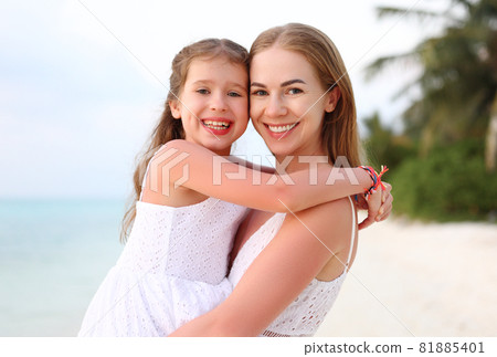 Happy mother and daughter hugging on beach 81885401