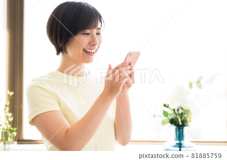 A woman looking at a smartphone by the window 81885759