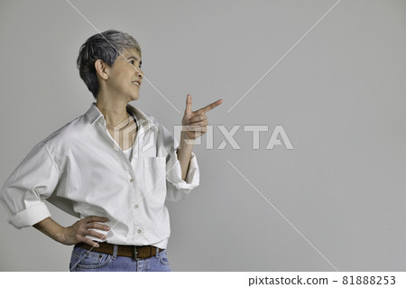 Asian woman pointing fingers up at empty copy space for text isolated on white background Asian woman pointing fingers up at empty copy space for text isolated on white background 81888253