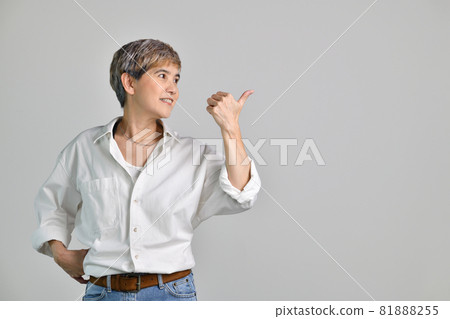 Asian woman pointing fingers up at empty copy space for text isolated on white background Asian woman pointing fingers up at empty copy space for text isolated on white background 81888255