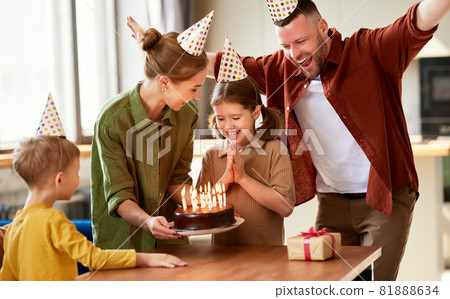 Excited little girl looking at cake and making wish while celebrating Birthday with family at home Excited little girl looking at cake and making wish while celebrating Birthday with family at home 81888634