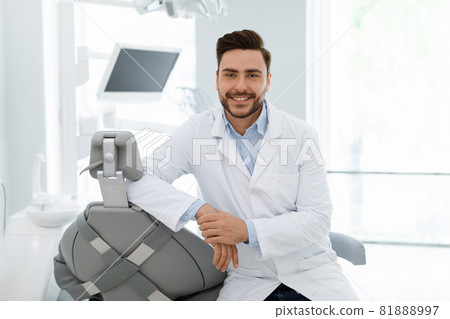Attractive dentist smiling at camera, posing in dental cabinet Attractive dentist smiling at camera, posing in dental cabinet 81888997