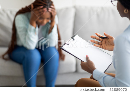 Desperate African American woman with nervous breakdown having session with psychologist at clinic Desperate African American woman with nervous breakdown having session with psychologist at clinic 81889070