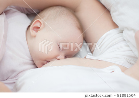 Mother holding newborn baby in an embrace and breastfeeding. Mother is breastfeeding her baby. Newborn breastfeed. Happy motherhood 81891504