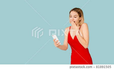 Online communication. Amazed woman. Digital life. Advertising background. Pretty surprised lady looking on smartphone screen isolated blue copy space. Online communication. Amazed woman. Digital life. Advertising background. Pretty surprised lady looking on smartphone screen isolated blue copy space. 81891505