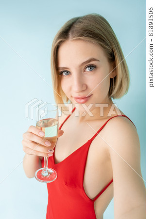 Online stream. Female blogger. Party selfie. Festive look. Pretty happy woman red dress glass champagne make invisible video isolated blue. 81891506