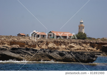 A lighthouse and small houses with tiled roofs on a stone cliff. High quality photo A lighthouse and small houses with tiled roofs on a stone cliff. High quality photo 81891980