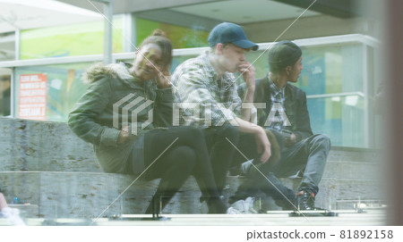 Friends sitting on staircase smoking 81892158
